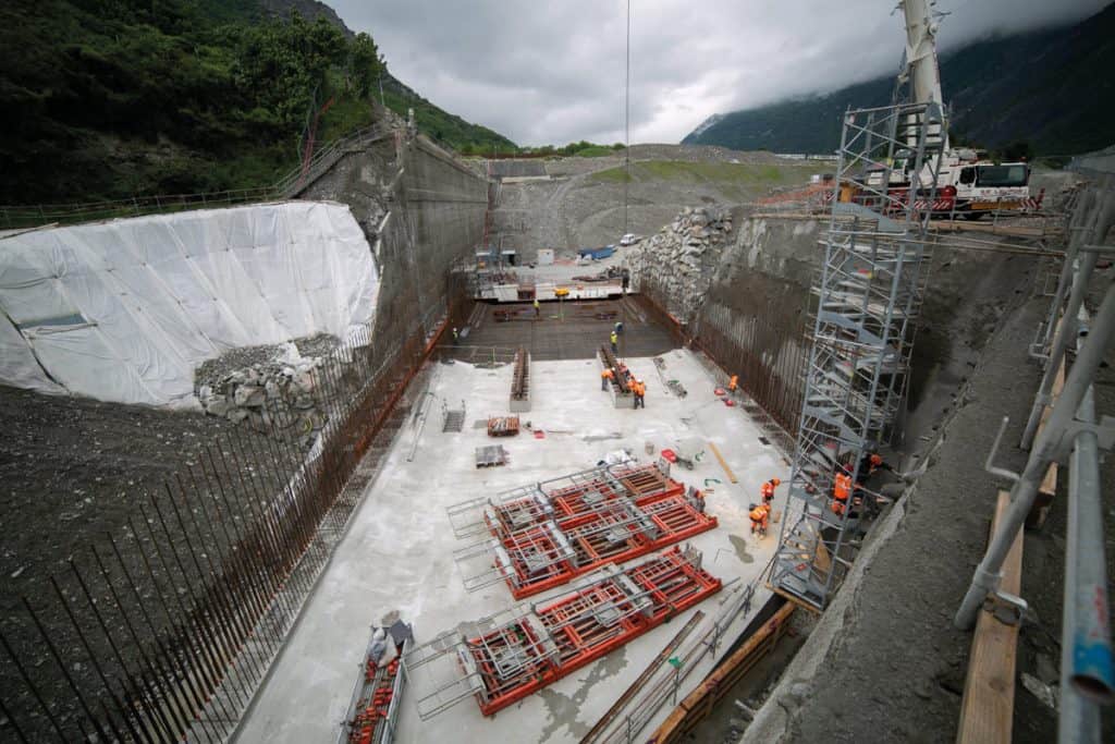 Photo en plongée du chantier. On voit des échafaudages et des travailleurs au fond d'un grand trou.