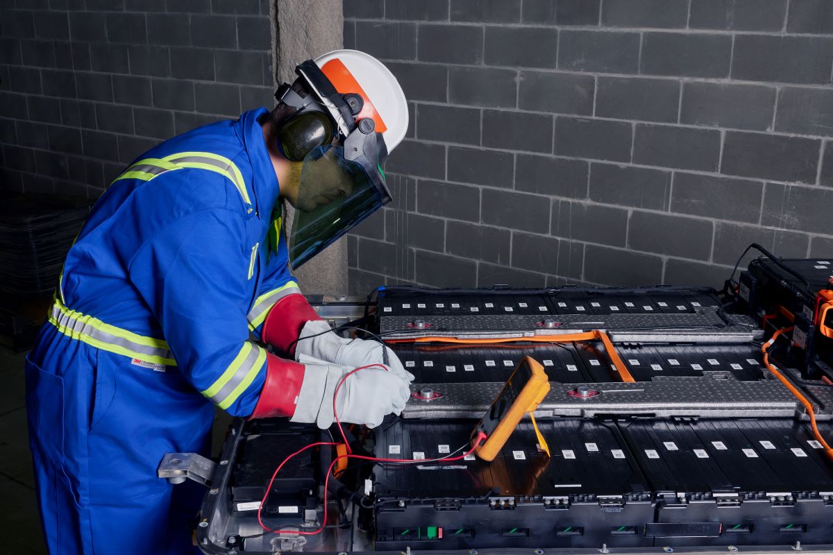 Un travailleur penché sur un bloc-batterie.