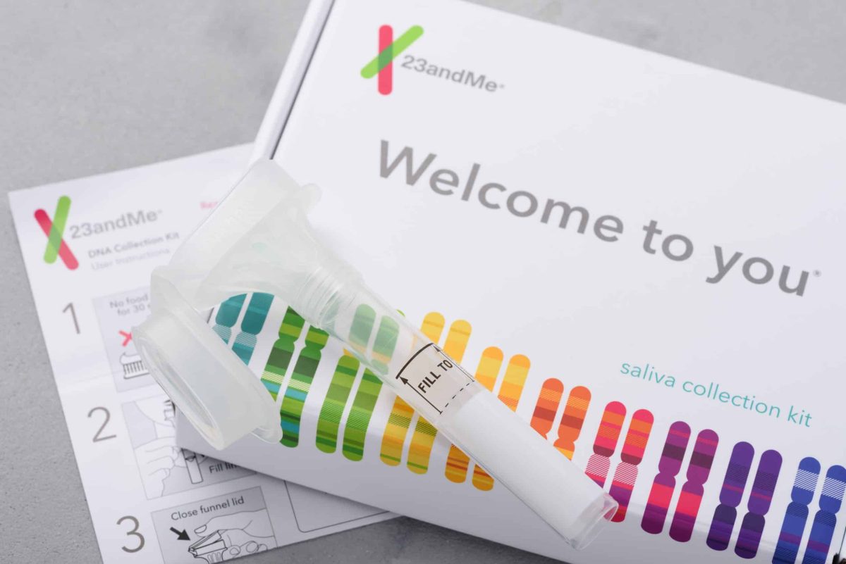 Photo d'un kit de test génétique maison. Une fiole de plastique est posée sur une boîte en carton colorée aux couleurs de l'entreprise 23andMe.